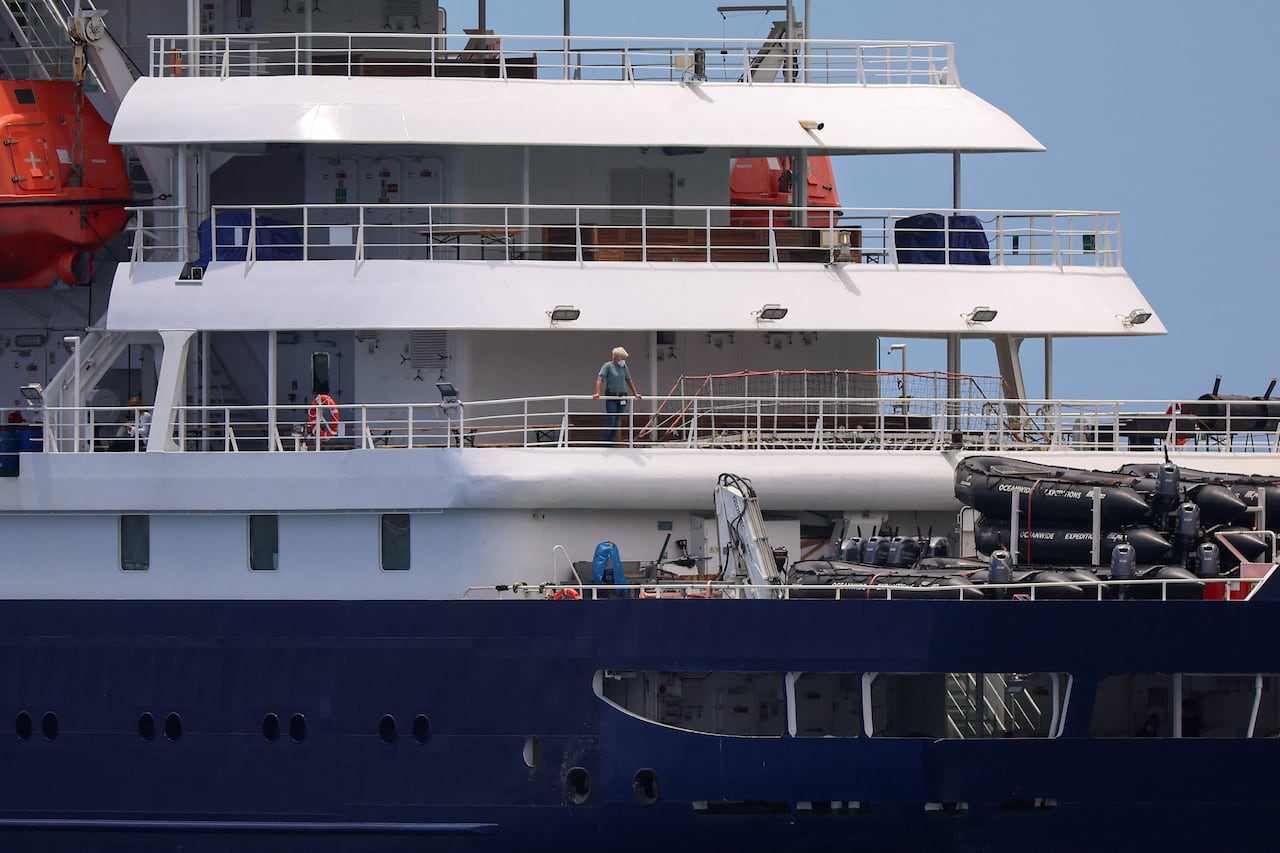 People stand looking out from a ship wearing surgical masks.