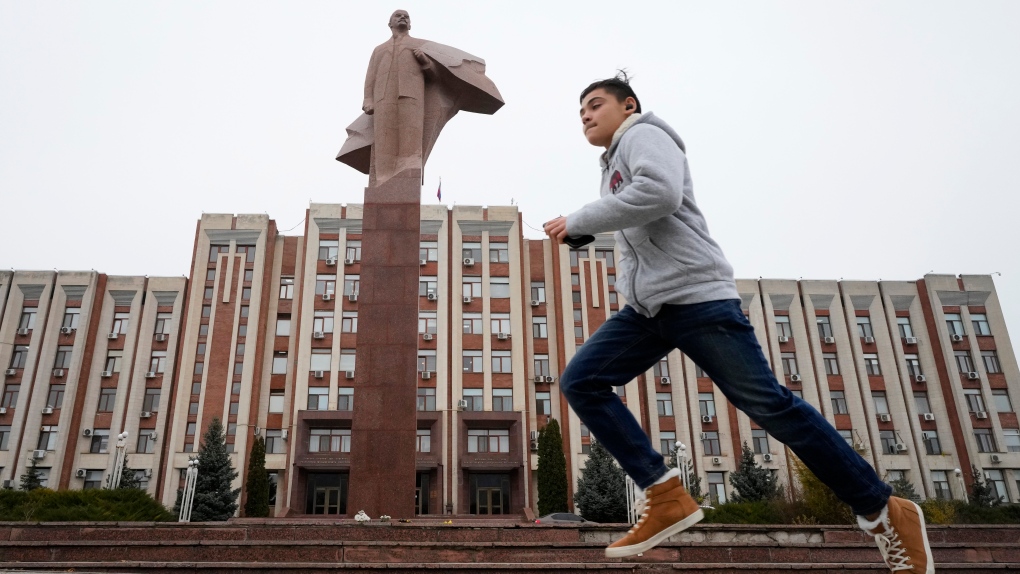 一个男孩跑过位于蒂拉斯波尔的苏联创始人弗拉基米尔·列宁的雕像，蒂拉斯波尔是德涅斯特河沿岸分离地区的首府，该地区是一个有争议的领土得到国际社会的认可，摩尔多瓦，2021 年 11 月 1 日星期一。（美联社照片/Dmitri Lovetsky） 