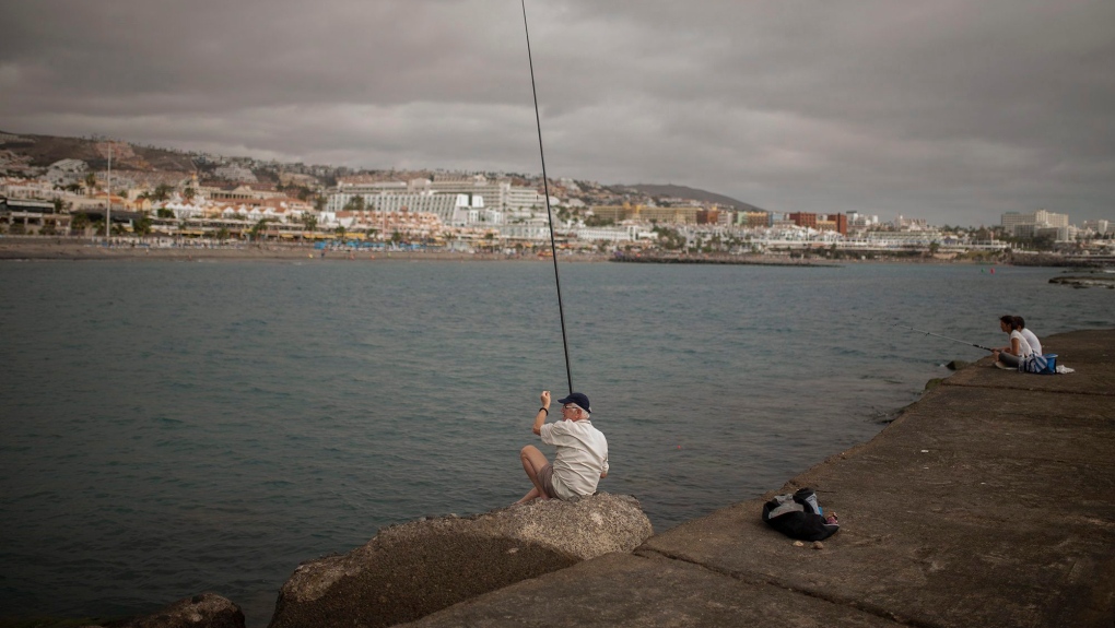 A man fishes on a breakwater in the Canary Island of Tenerife, Spain, Sunday, March 1, 2020. (AP Photo/Joan Mateu)