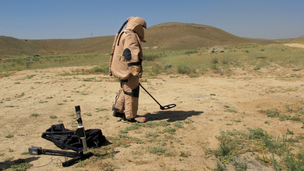 一名男子在简易爆炸装置拆除过程中用金属探测器搜寻地雷2013 年 6 月 11 日星期二，阿富汗喀布尔郊区举行降雨演习。（美联社照片/Kay Johnson）