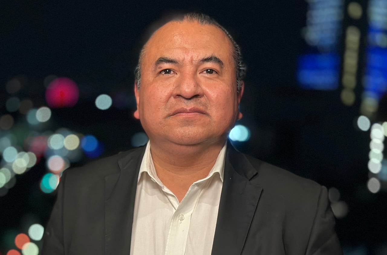 A man looks into the camera with a nightime backdrop.