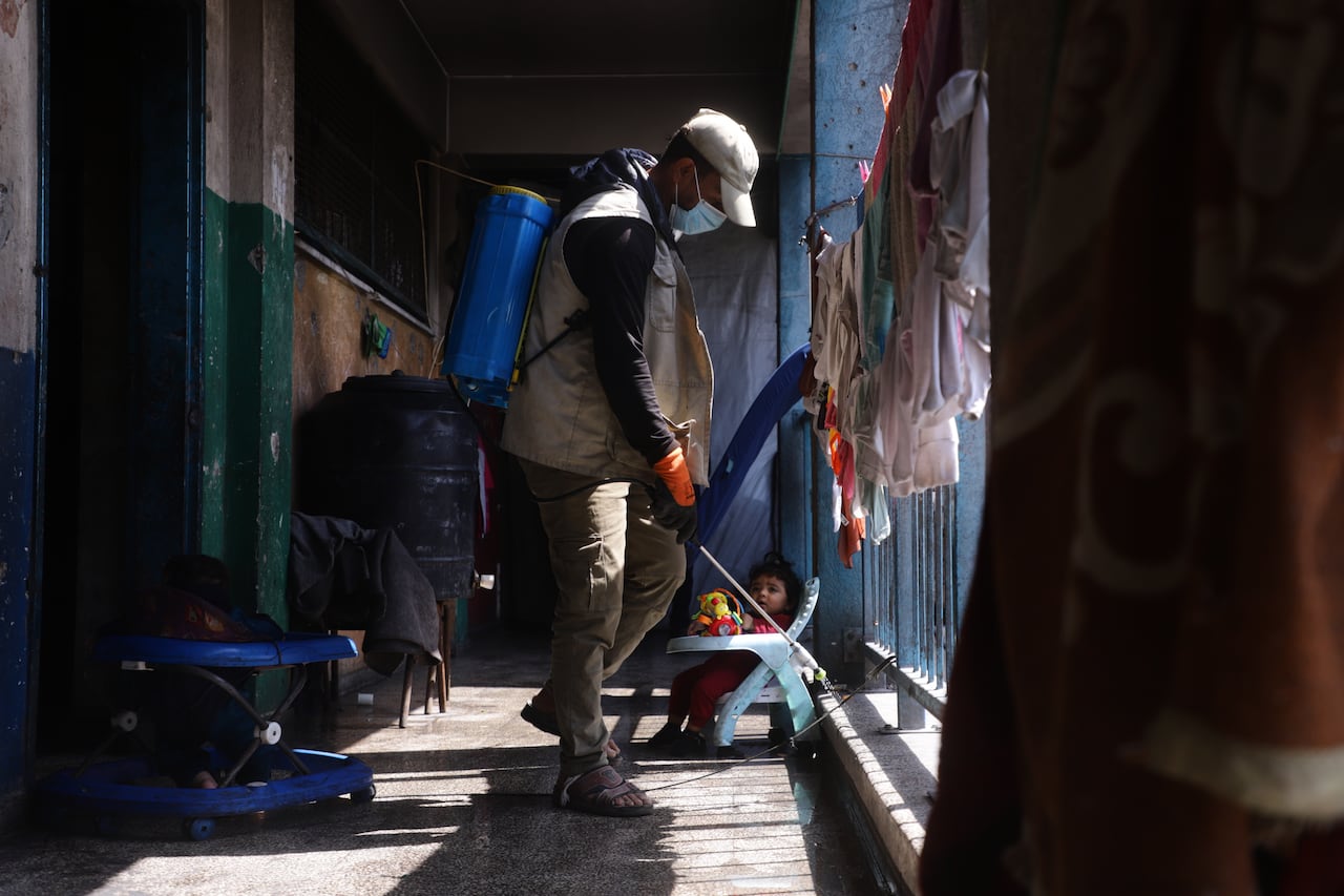 a man sprays pesticides in a school hallway