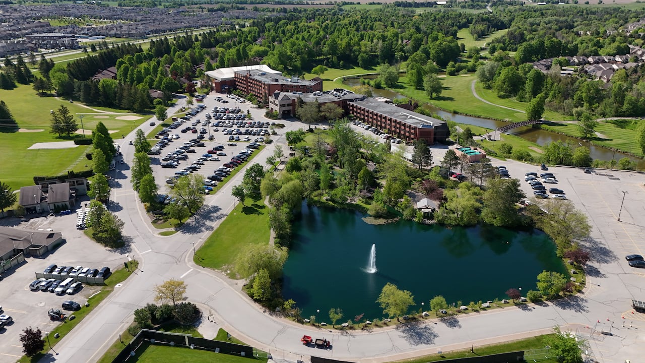 An aerial view of a hotel and conference centre, surrounded by a golf course and some suburban housing.