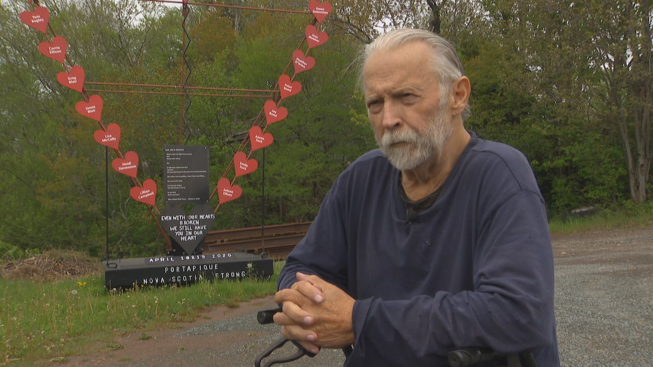 A man sits in front of a sculpture he made to commemmorate the victims of the 2020 mass casualty event in Nova Scotia.