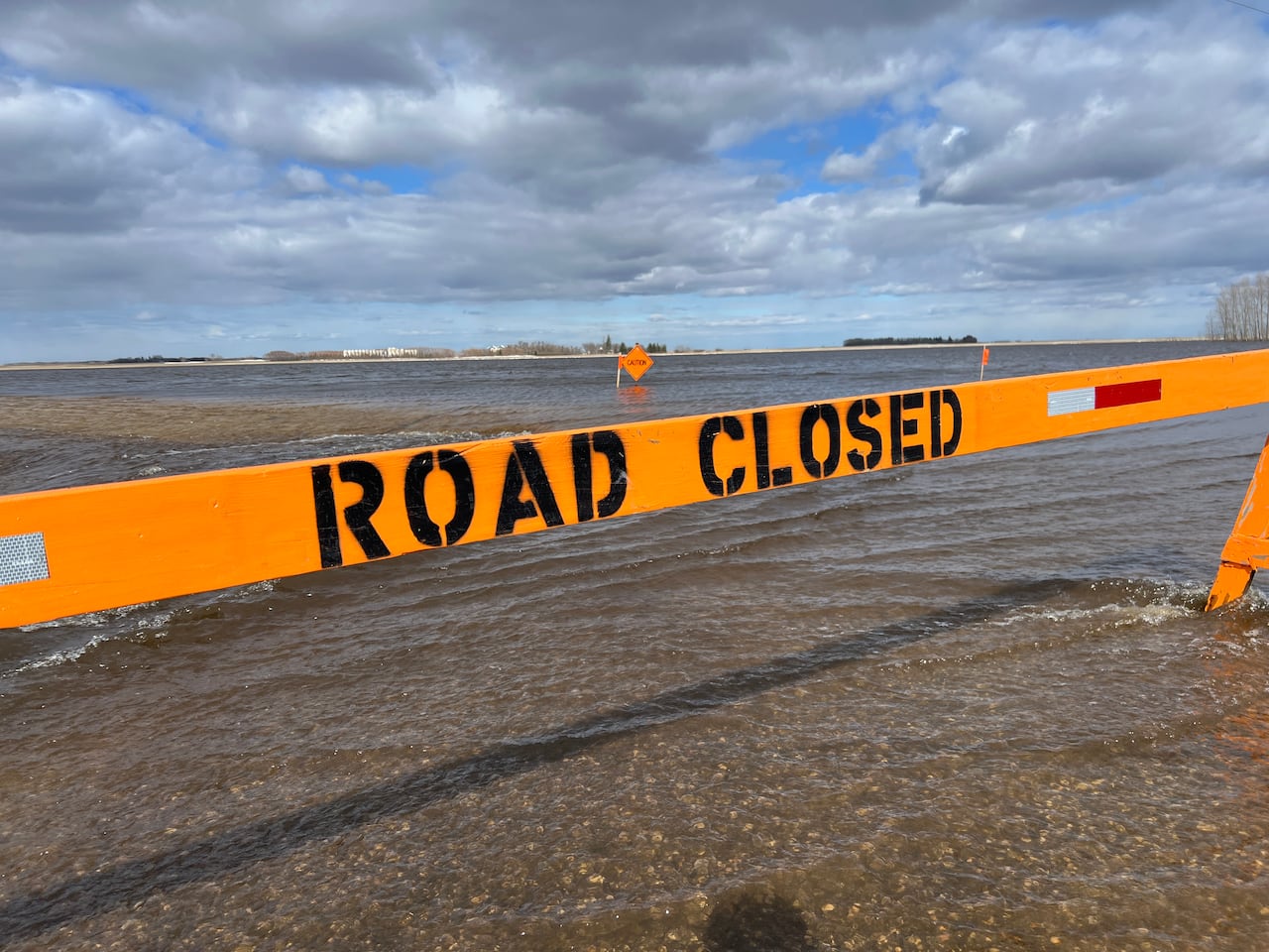 An orange sign says road closed and then all you can see is water.