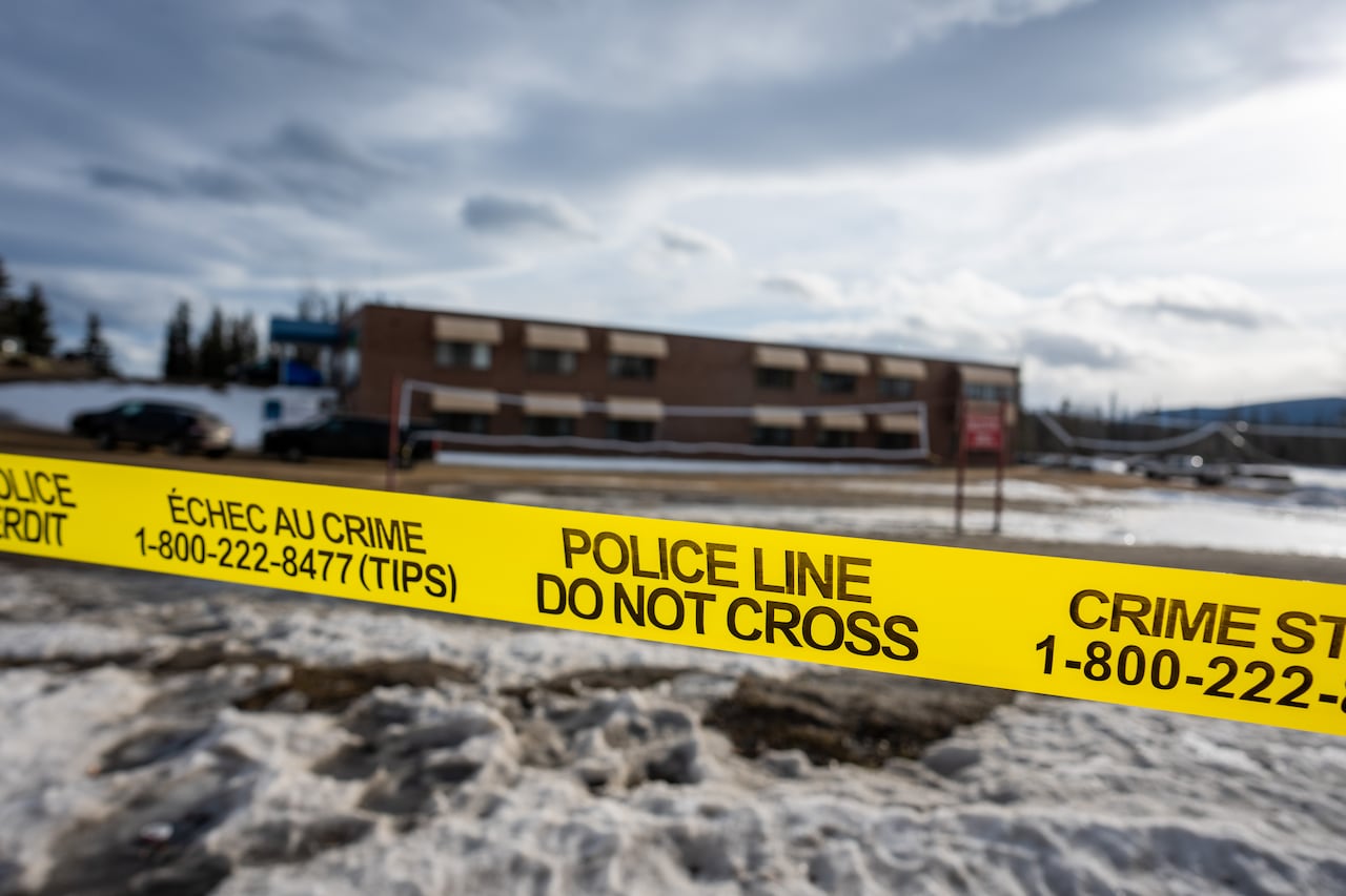 Police tape in front of a brick school.