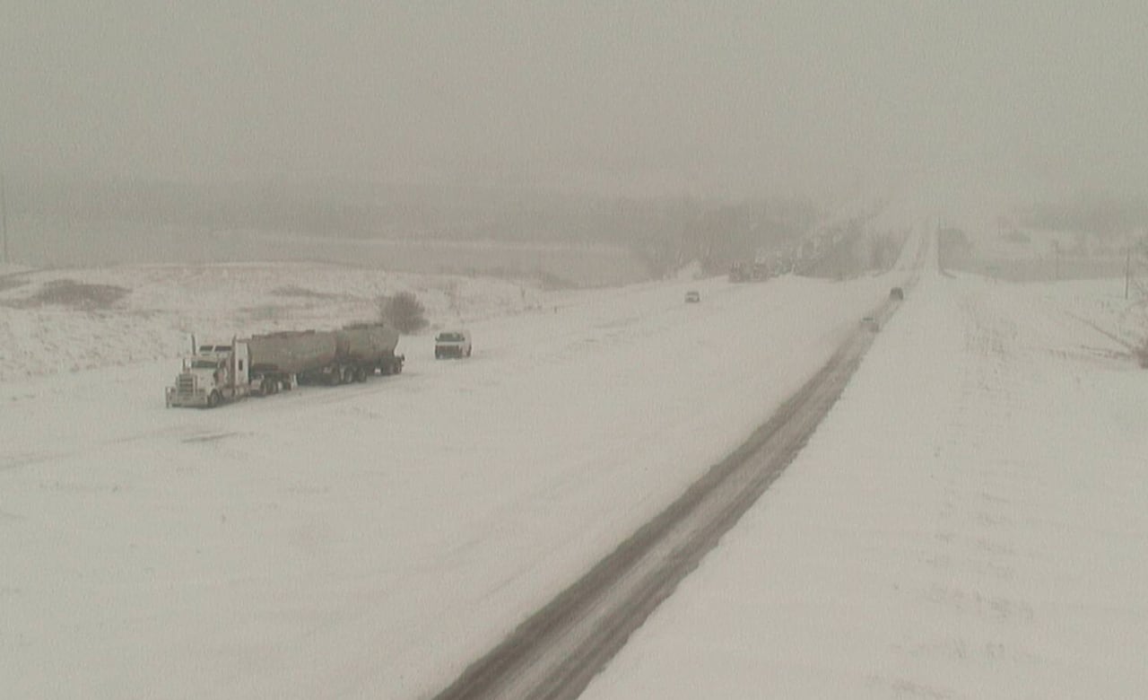 Snowy roads and a semi stopping backed-up traffic.