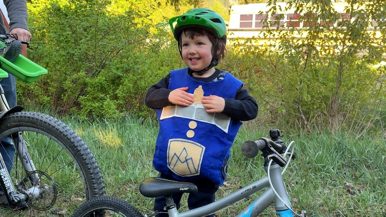 A young boy stands by a bike.