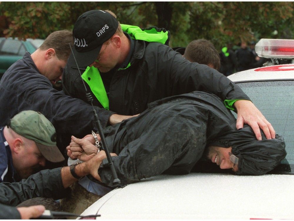Police pin accused murderer Cosmo Jacobson to a cop car after capturing him in a gunpoint takedown at a posh Whitby home. Jacobson had escaped for 8 hours while being transferred to a Whitby court.
