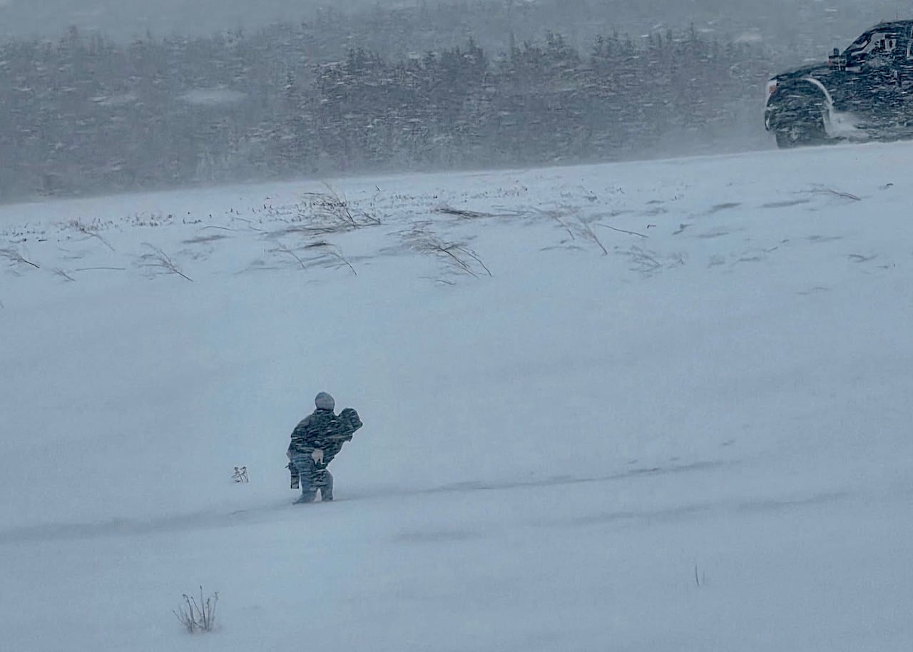 A man walks outside with a child on his back in the snow.