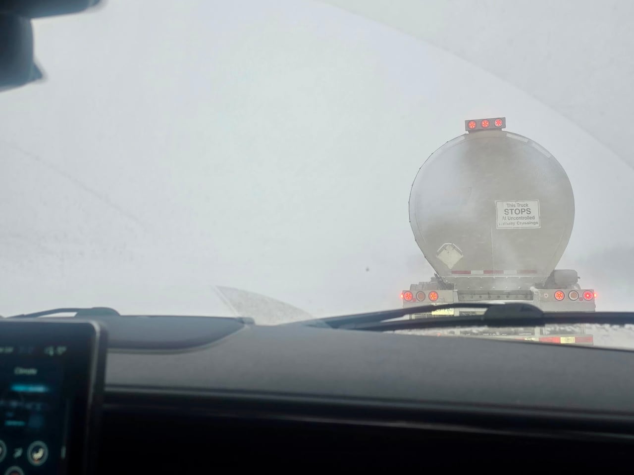 A car window shows low visibility in the snow.