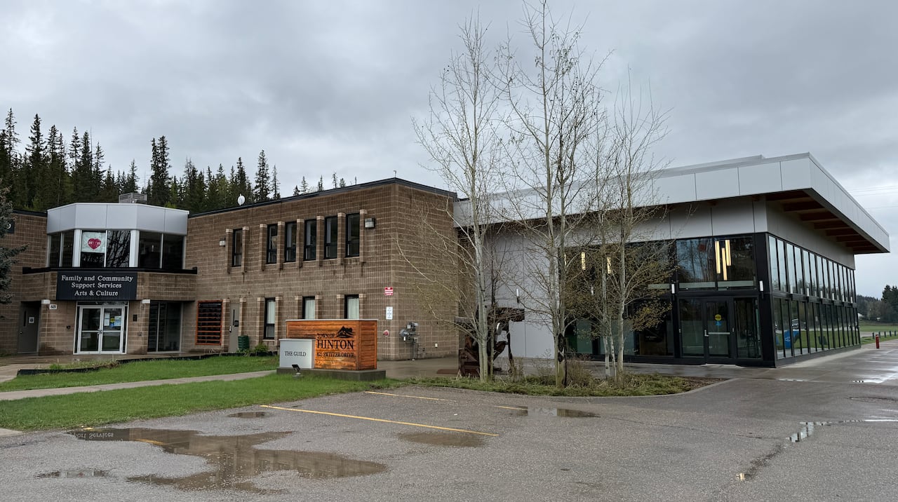 A building and a parking lot on a gloomy day with some trees.