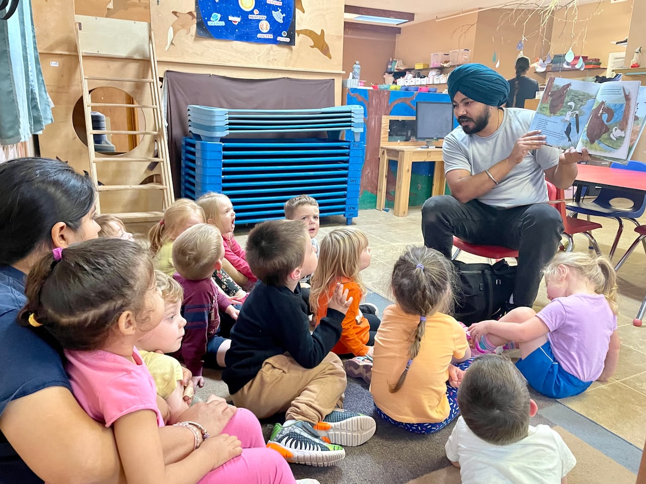 Child-care working reading a book to kids.