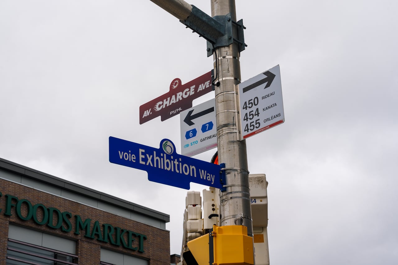 A red "Charge Avenue" sign is installed at the corner of Bank Street and Exhibition Way on April 30.
