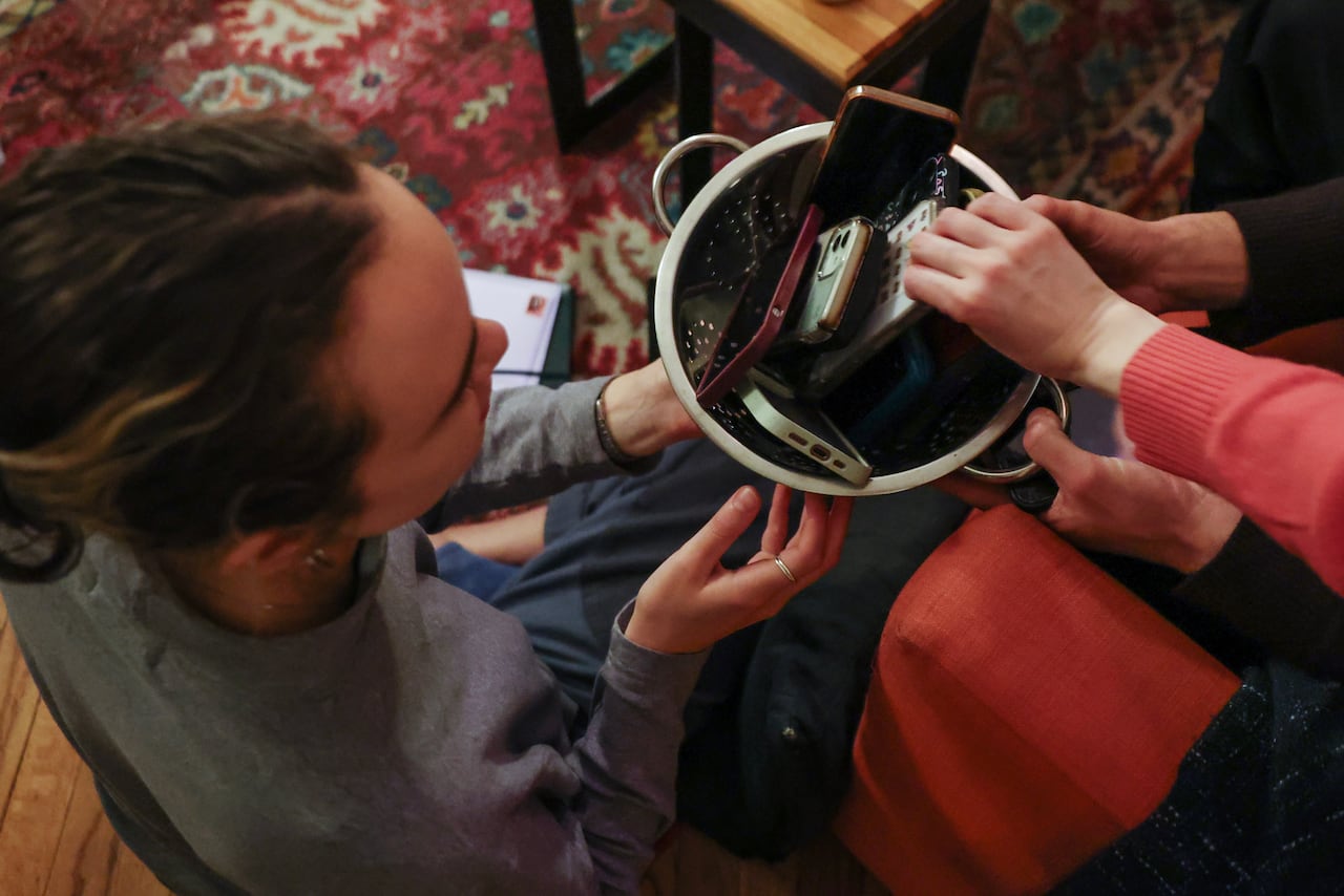 A shot of hands placing smartphones in a bowl