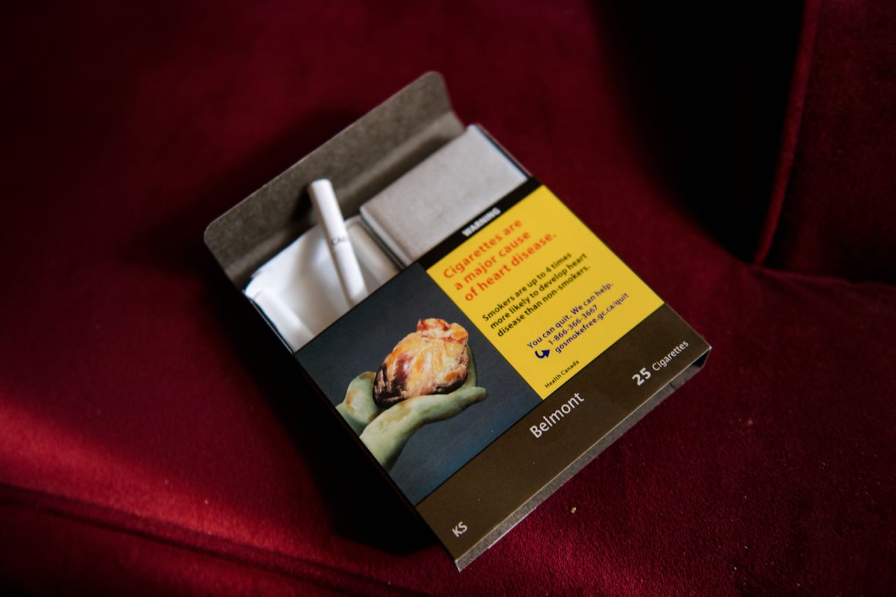 A pack of cigarettes is seen in front of a red background.
