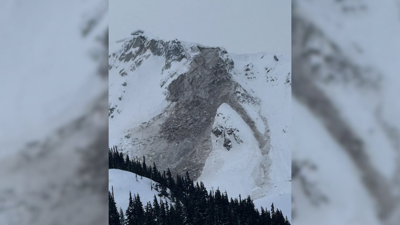 A snowy mountain with a rockfall down one side. 