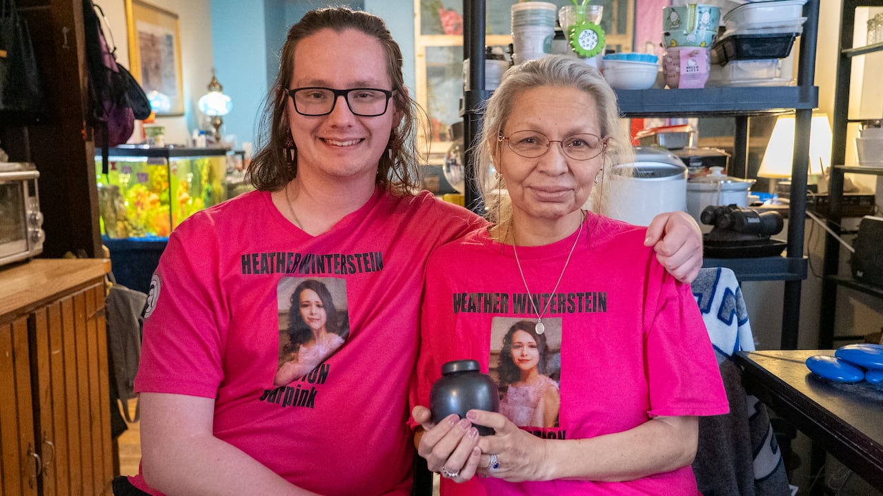 young man and woman wearing a pink t shirt with photo as woman holds urn