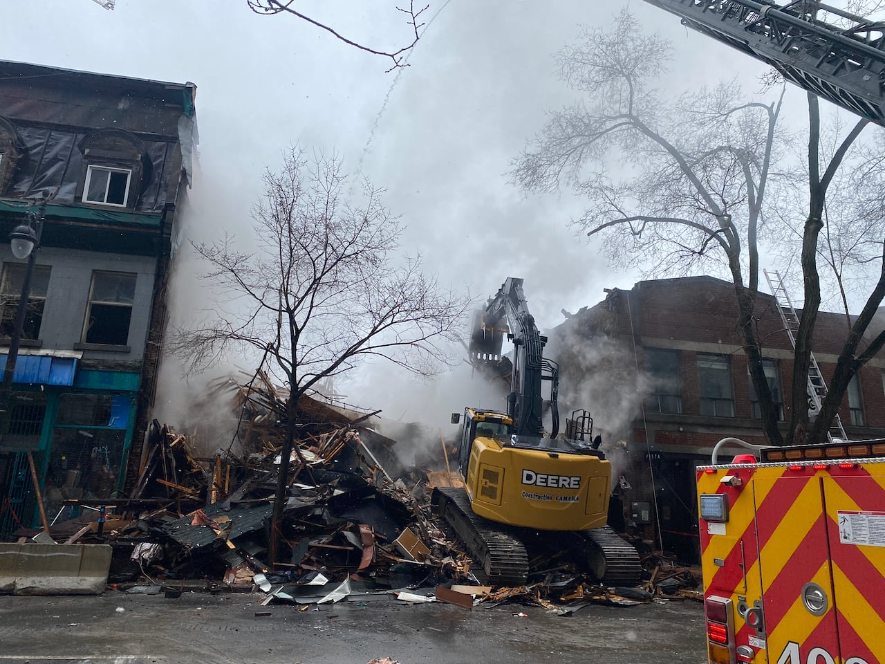 Tractor demolishing building that is still smoldering from fire