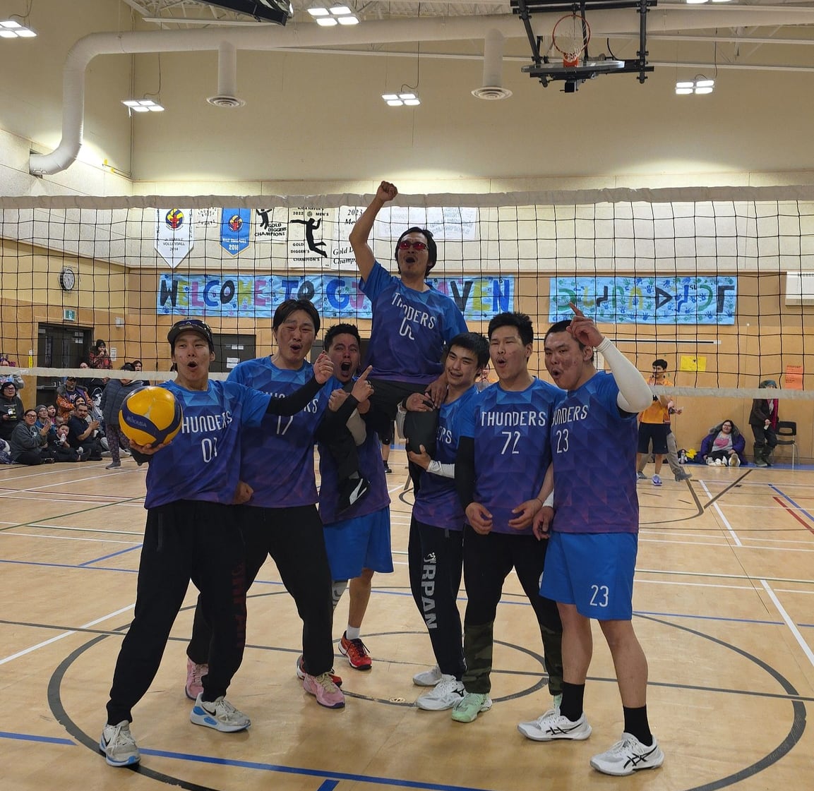 men standing in front of a volleyball net, pumping their fists