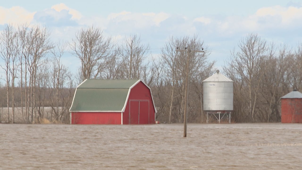 A red barn surrounded by water.