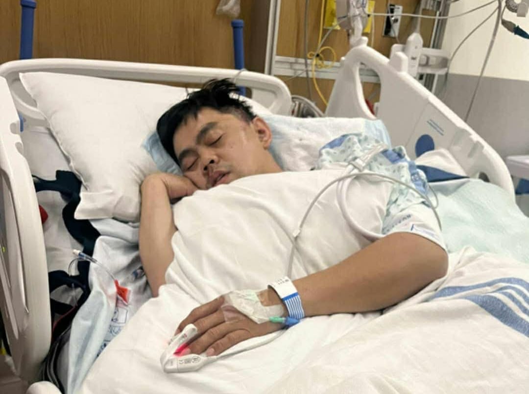 A man lies asleep in a hospital bed.