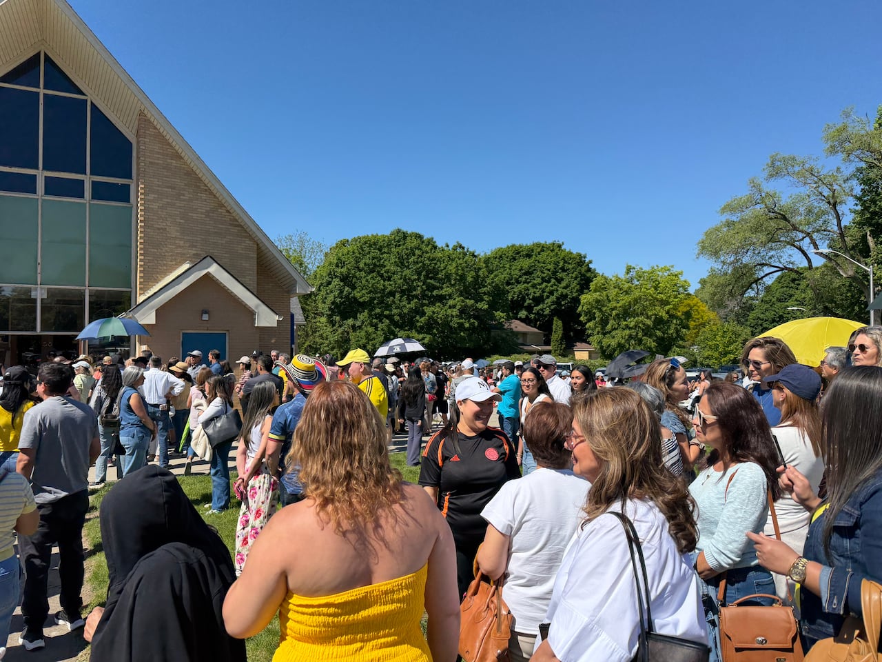 Lots of people standing in the grass in front of a church