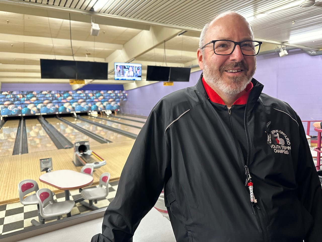 A guy standing ahead of bowling lanes.