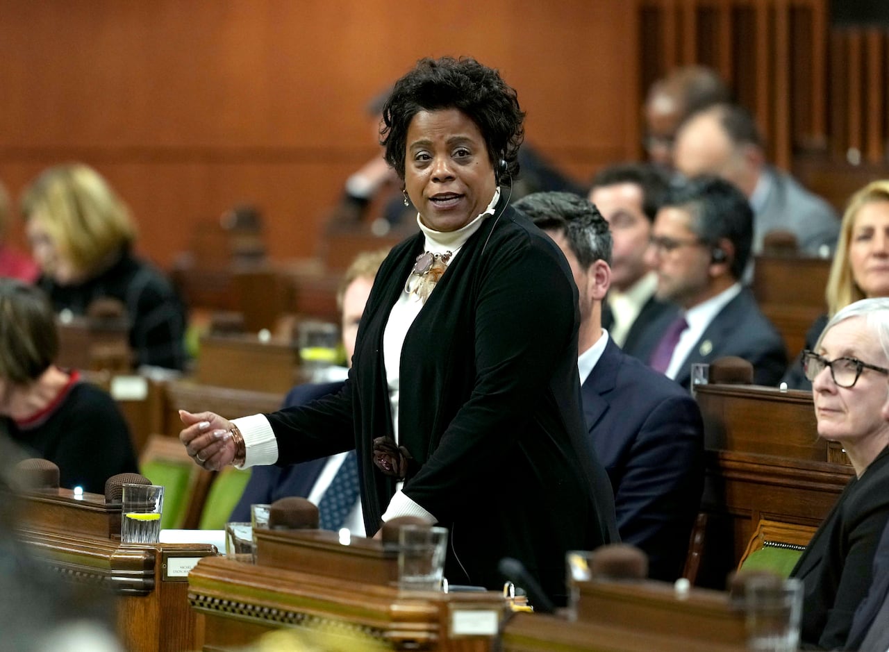 A woman stands at a wooden pew.