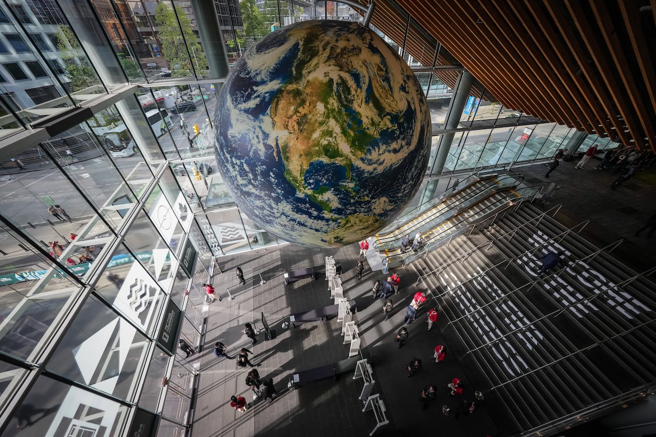 People walk under a large globe as they arrive for the 76th FIFA Congress in Vancouver on Thursday, April 30, 2026.