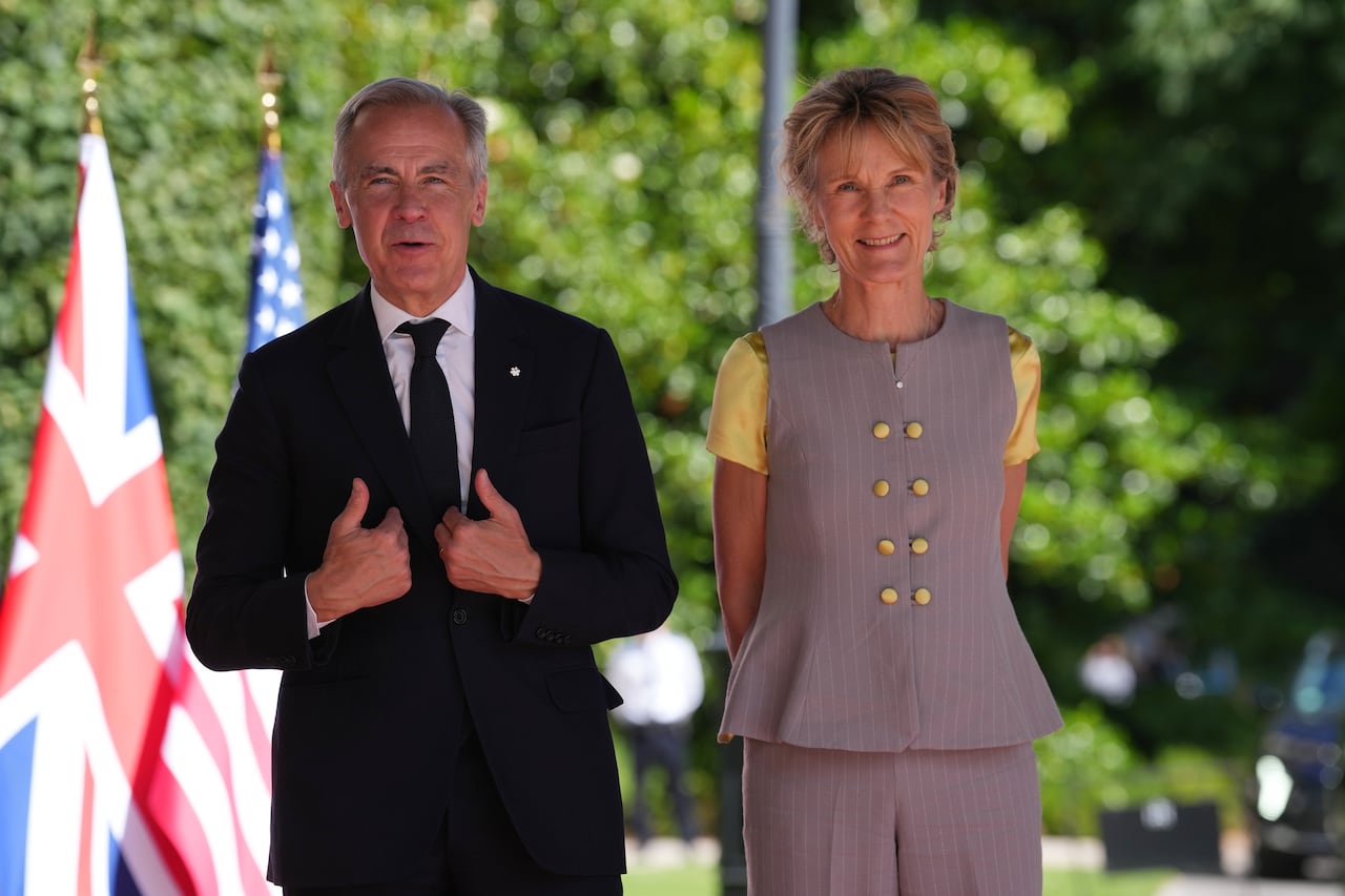 A man and woman standing outside in front of some flags.