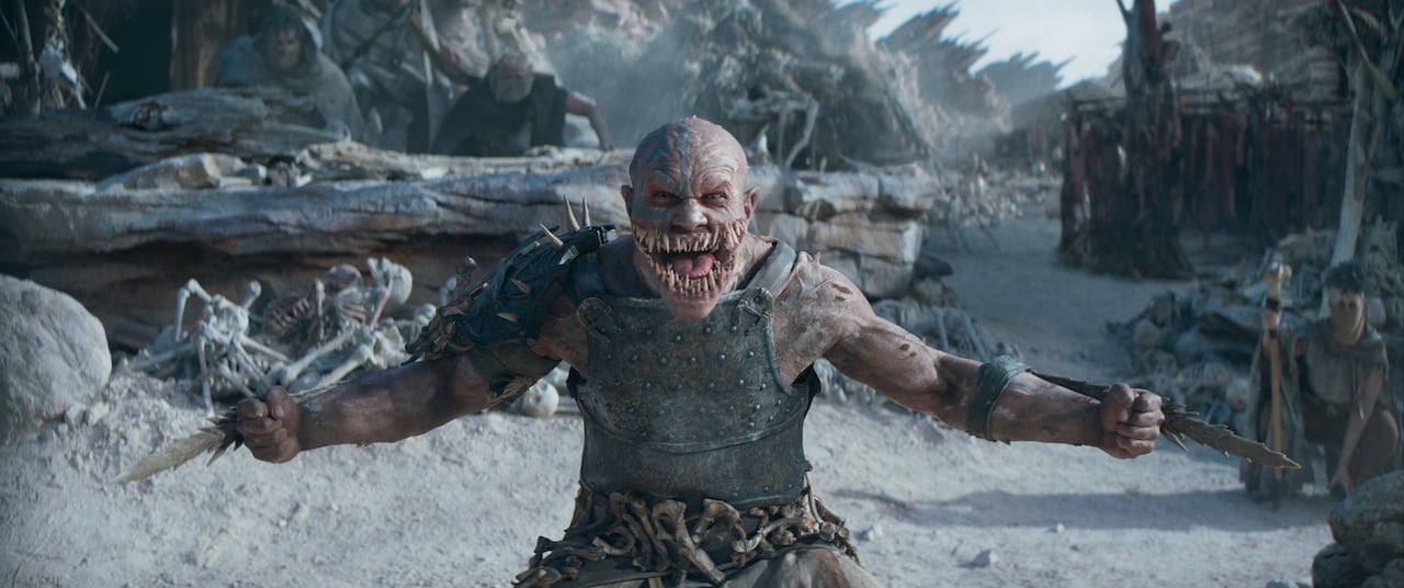 A monster with large teeth yells at the camera.