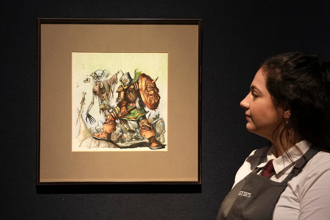 A woman in an auction or museum location looks at a framed drawing of a fighter in armour.
