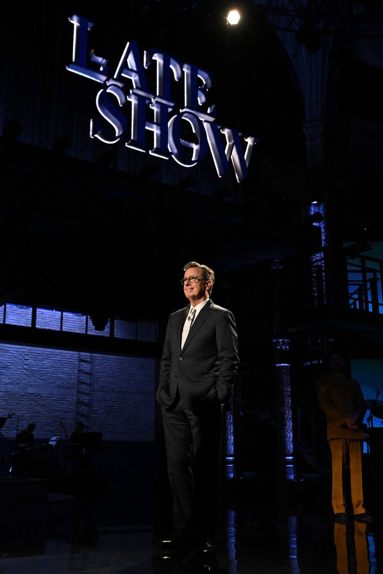 Big sign that says Late Show hanging over a man in a suit looking toward the audience.