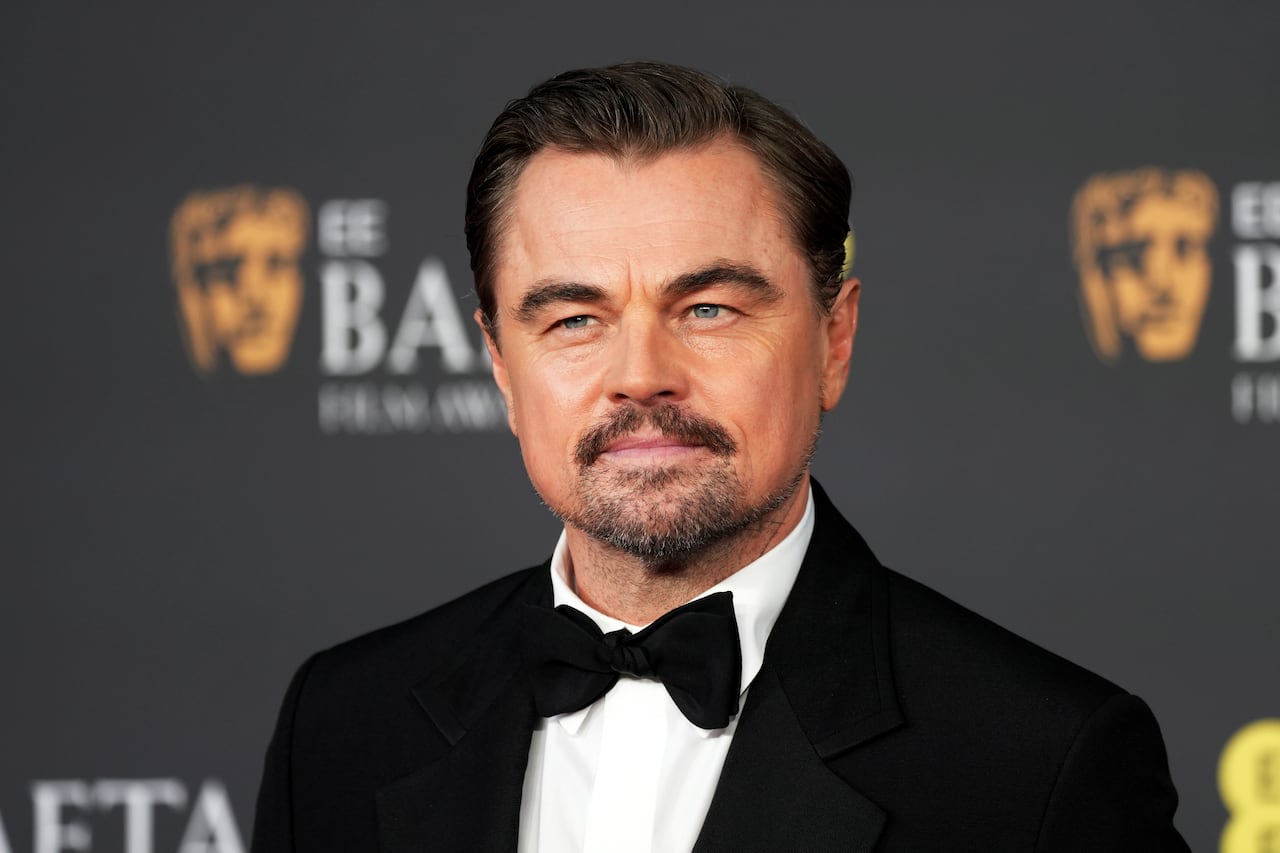 Man in tuxedo with mustache poses for camera.