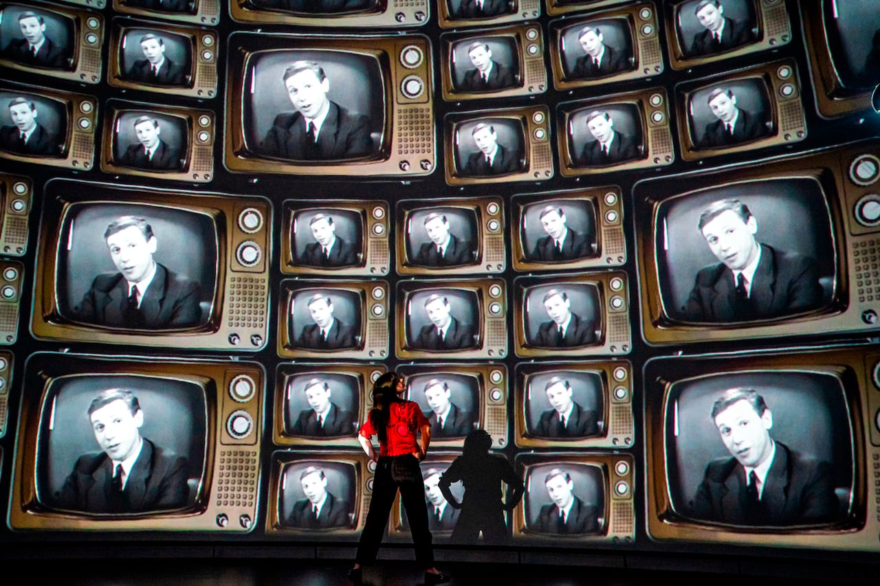 hundreds of television screens with broadcaster and naturalist David Attenborough's face, from when he was a young broadcaster, projected on a 360 degree screen inside a dome
