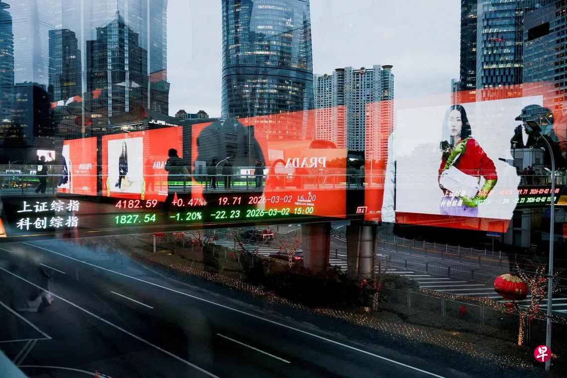 图为2026年3月2日，行人在中国上海陆家嘴金融区的人行天桥上穿行，背景的电子显示屏正展示上海股市指数。 （路透社档案照片）