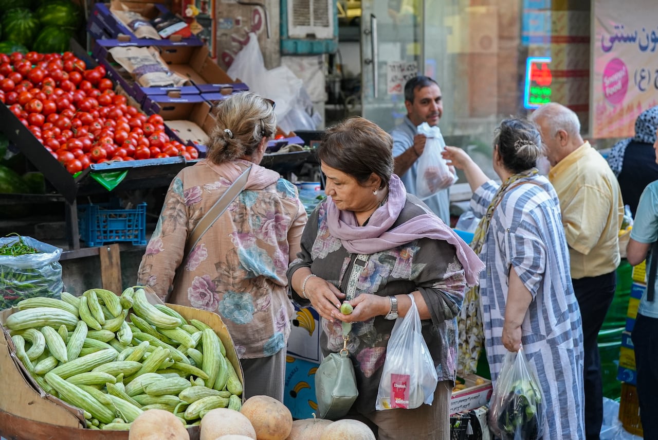 People shop at a market for vegetables.