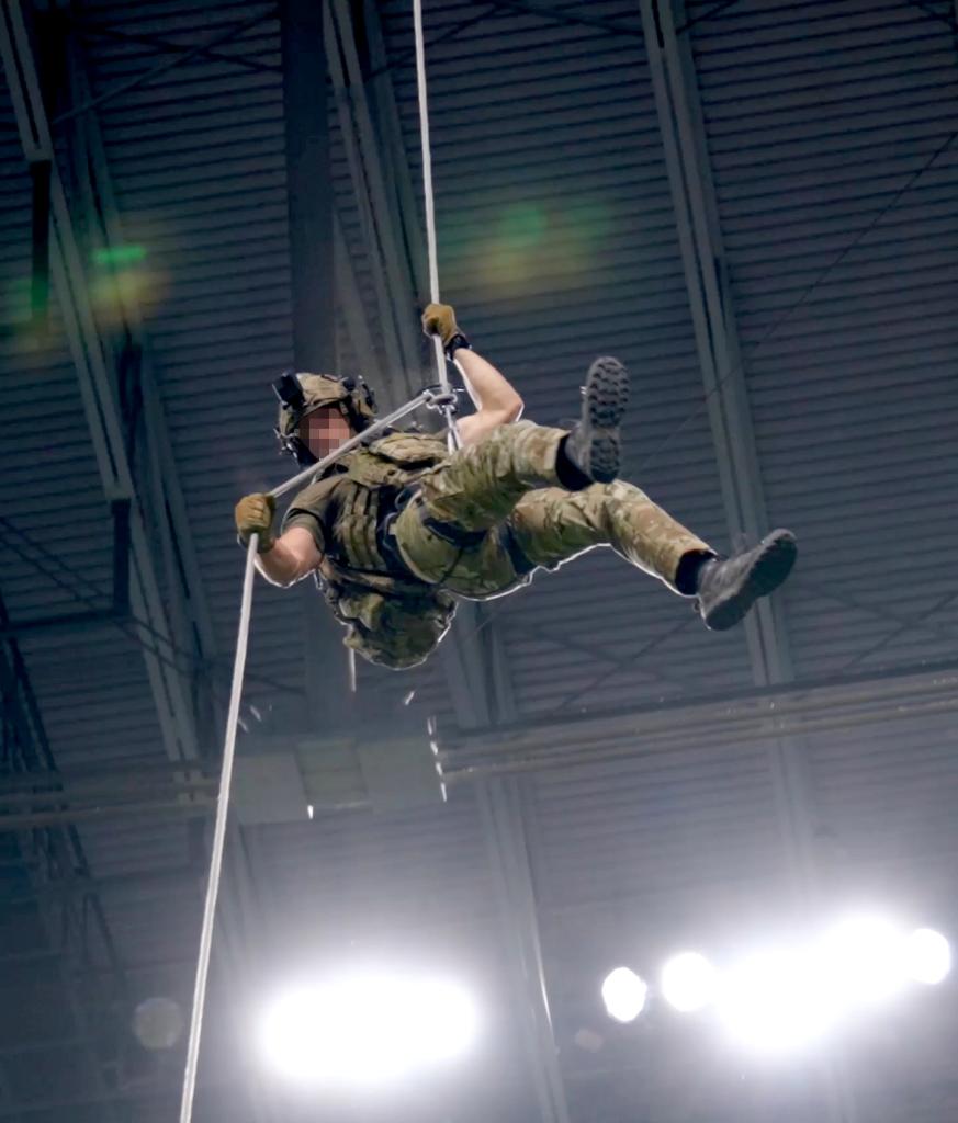 An airman rappels from the Alamodome stadium rafters during an earlier demonstration.