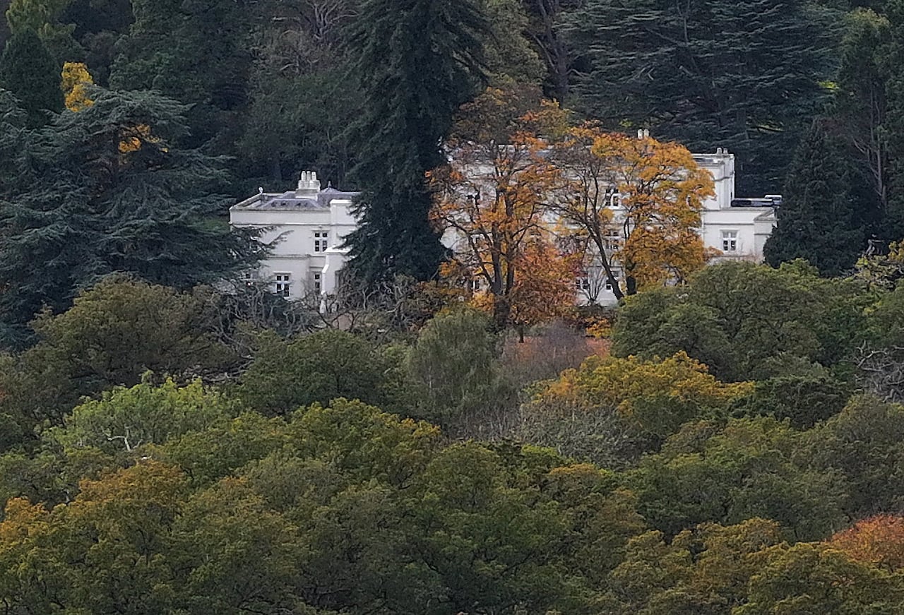 A drone shot of a large mansion partially behind trees.