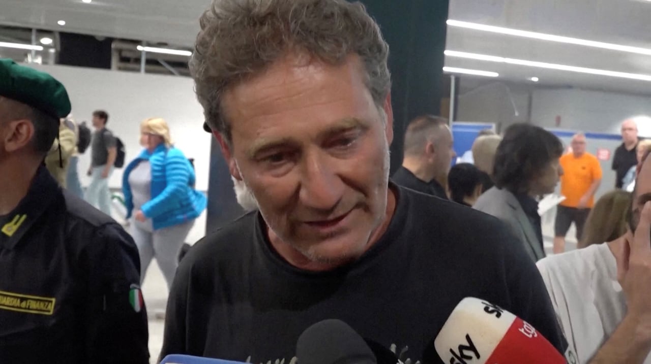 A man speaks into multiple microphones held up in front of him.