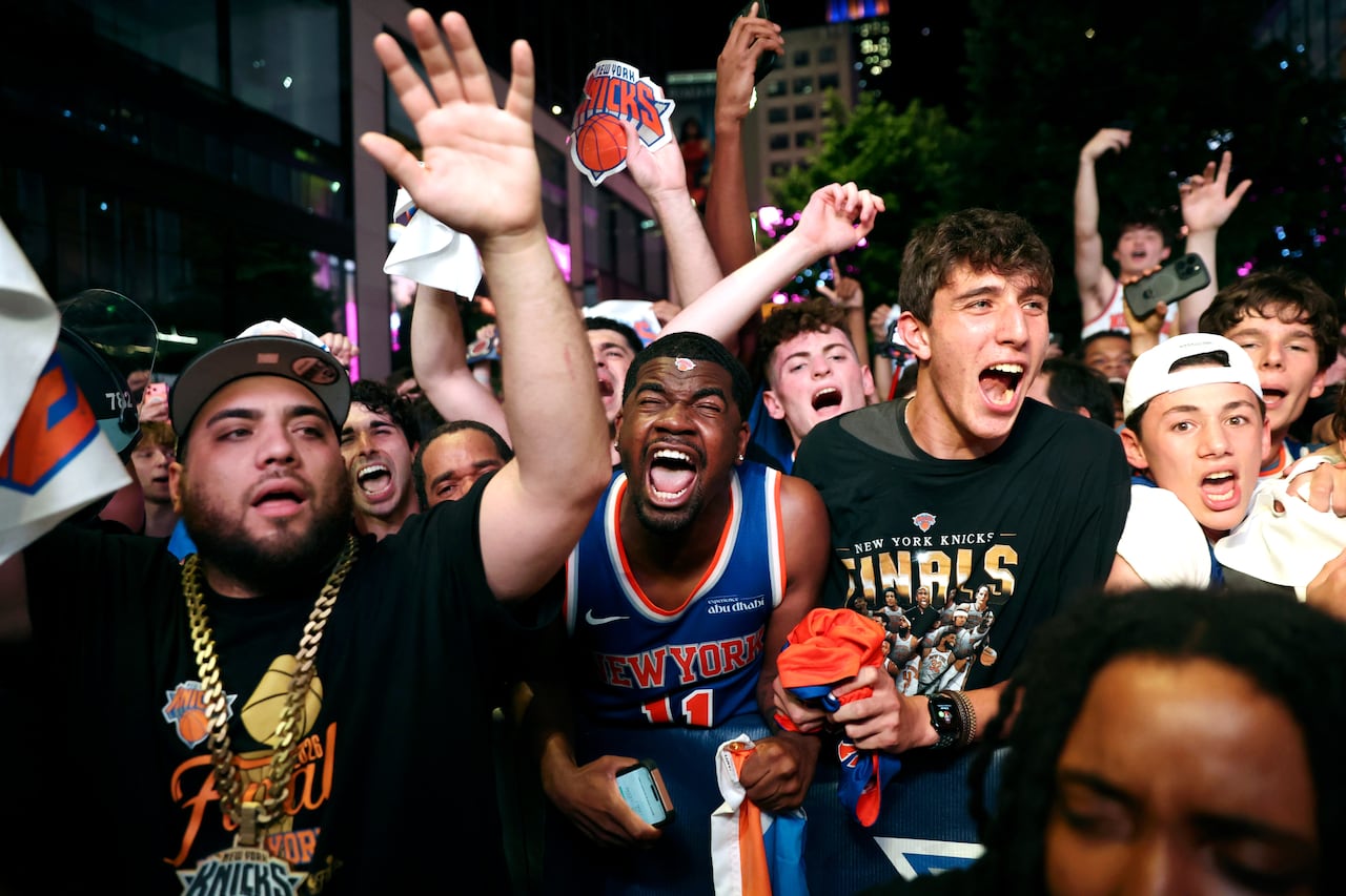 Fans wearing jerseys and gold necklaces scream in celebration.