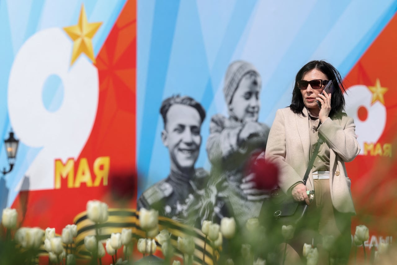 A woman talks on the phone in front of a banner for the Victory Day military parade, marking the anniversary of victory over Nazi Germany in World War Two, in central Moscow, Russia, May 4, 2026. REUTERS/Ramil Sitdikov