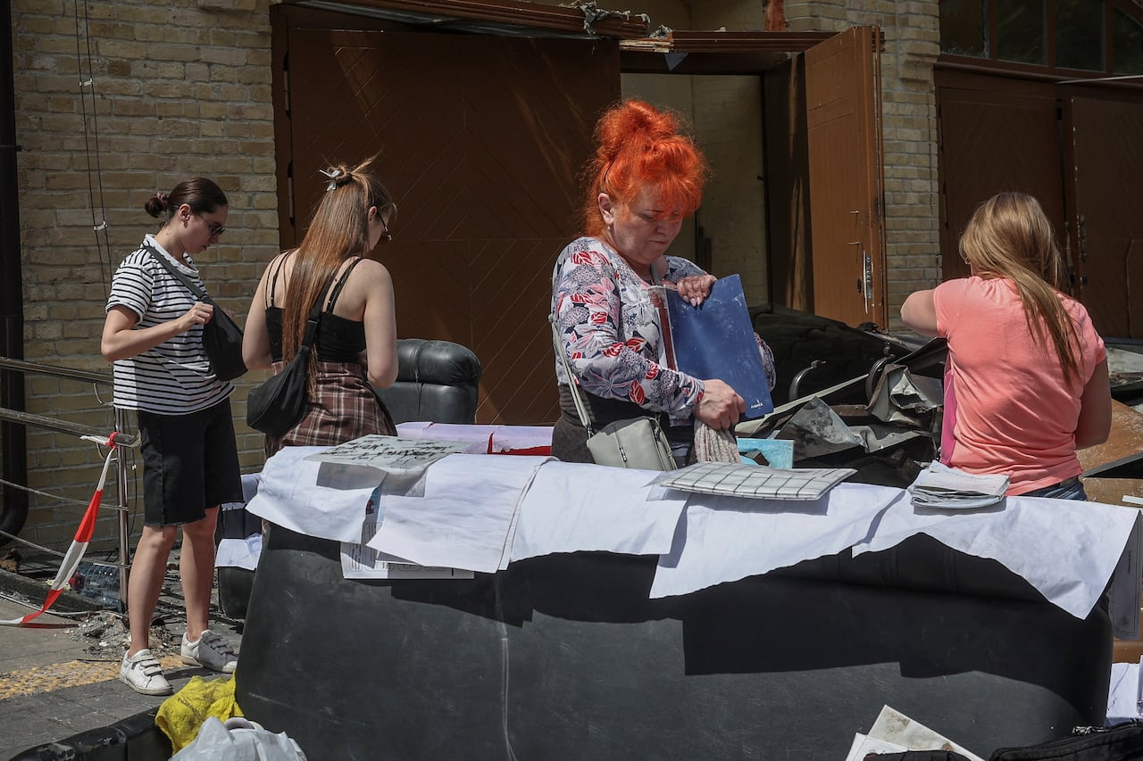 People stand outside of a building where items are placed on the ground.
