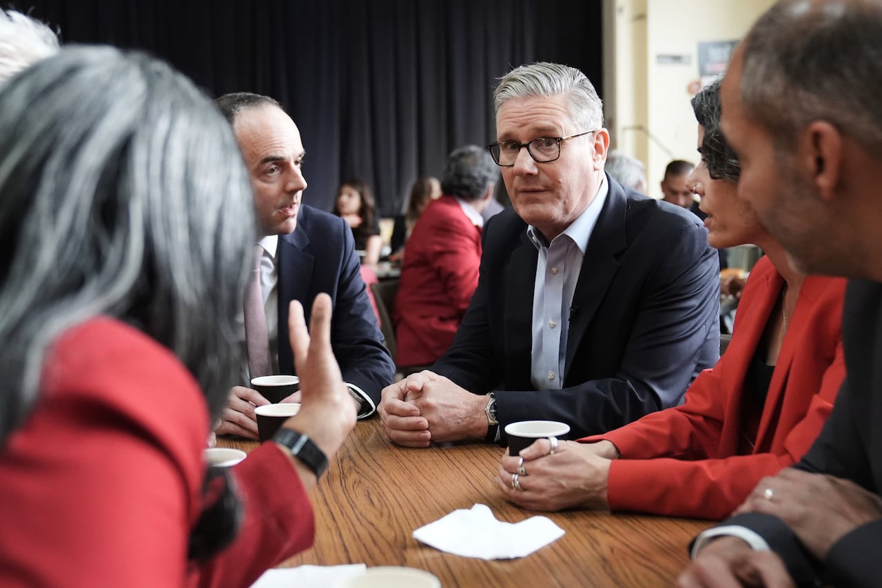 A man sits at a table looking concerned as people sit around him and look in his direction.