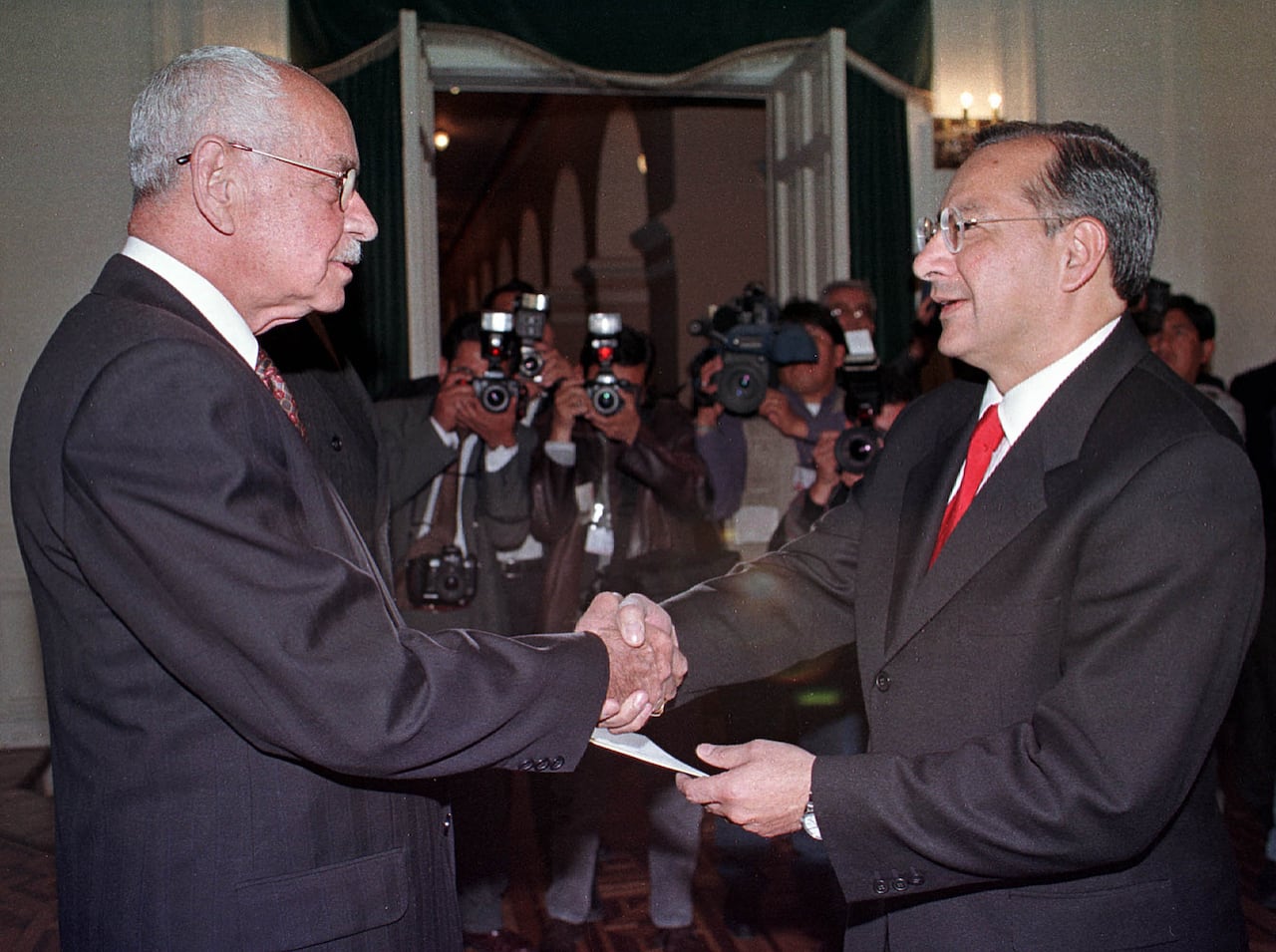 A photo taken Aug. 3, 2000, showing Hugo Banzer (left), then the president of Bolivia, shaking hands with Victor Manuel Rocha (right).