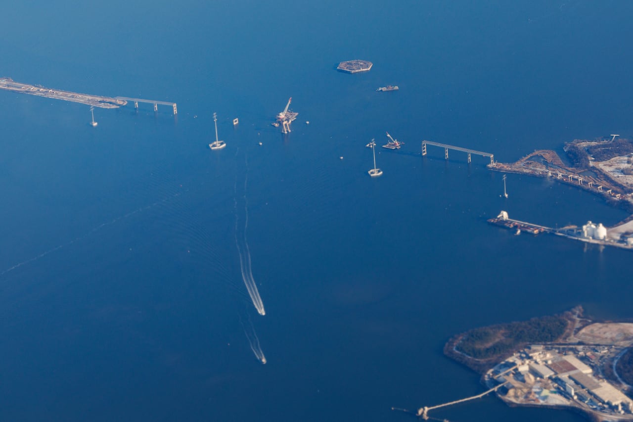 An aerial view shows a bridge over a body of water which has been severed.