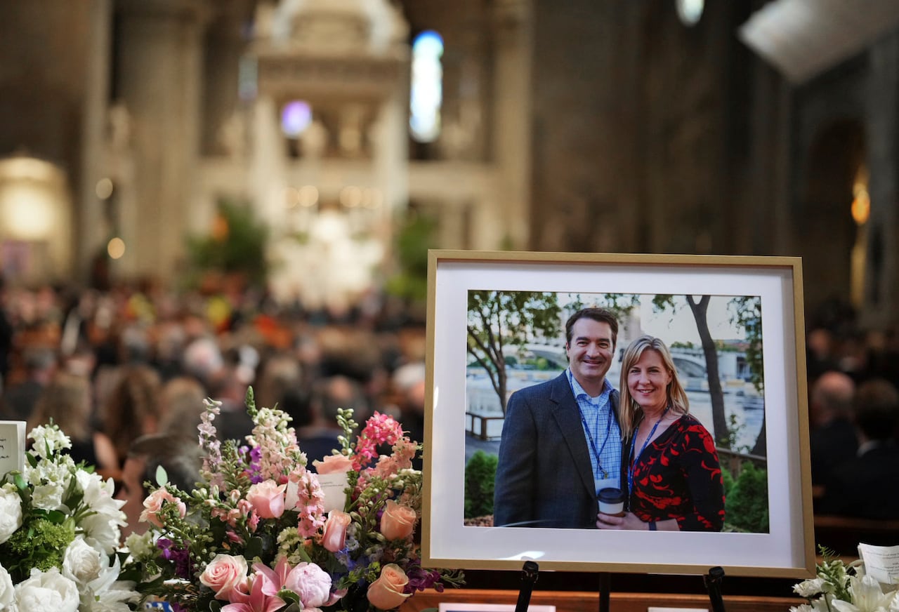 A framed photograph of a man and a woman is shown in close near flowers inside a church.