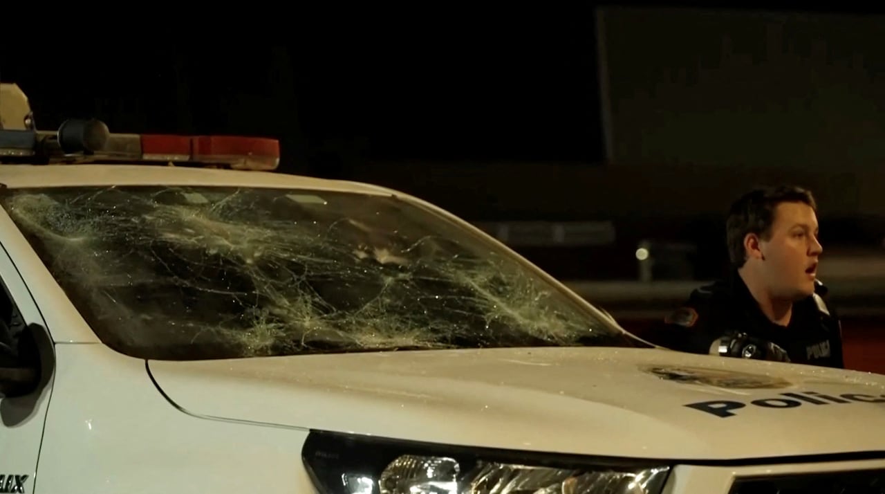 Police officer next to damaged car.