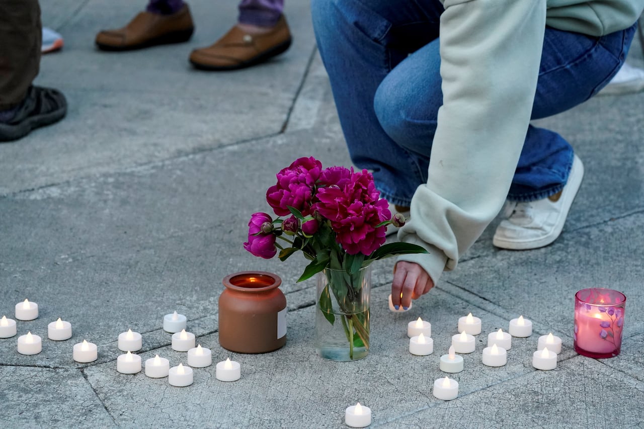 A cropped image showing a person's hand placing a candle at a vigil in Longview, Washington.